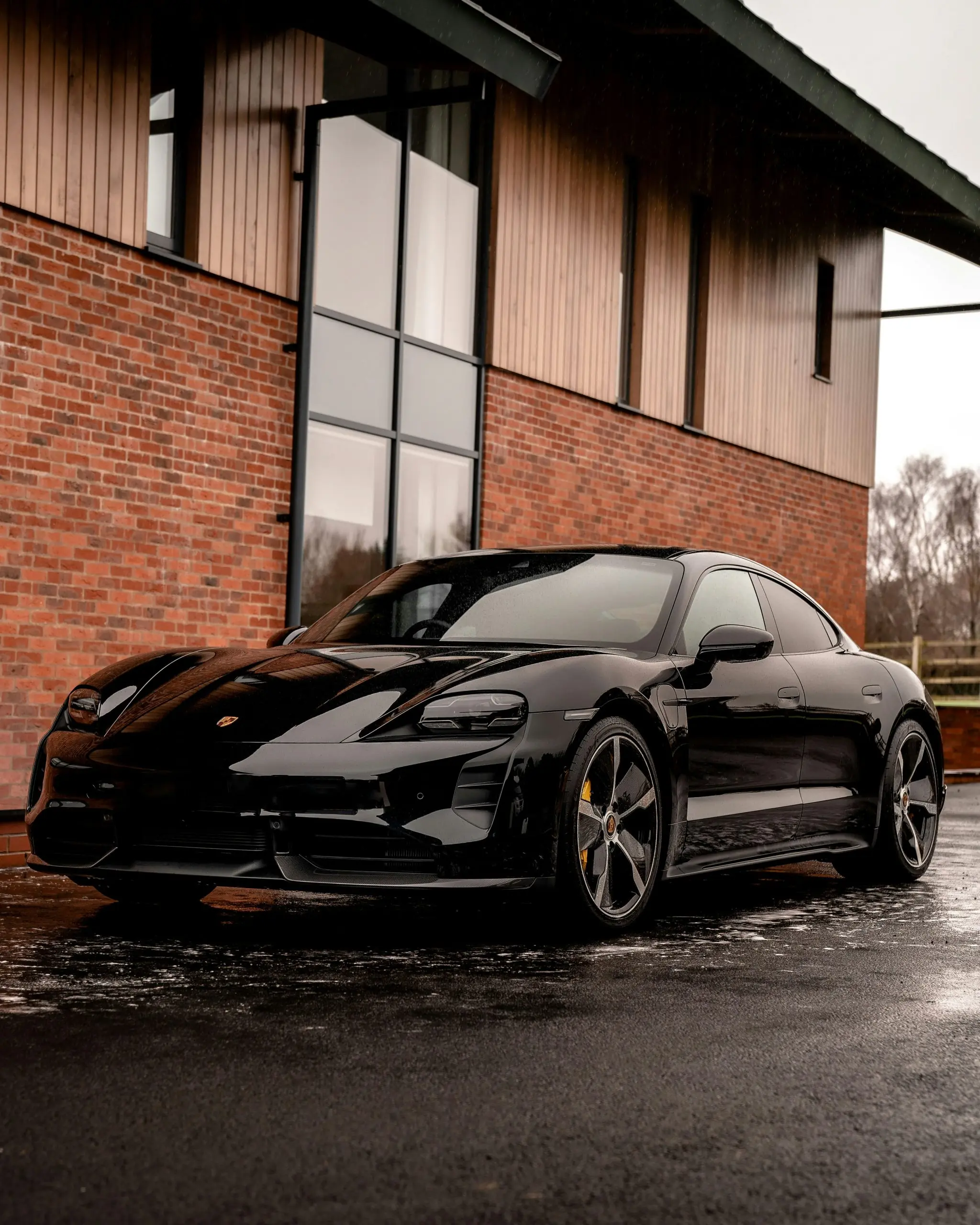Schwarzer Porsche Taycan vor einem Backsteingebäude
